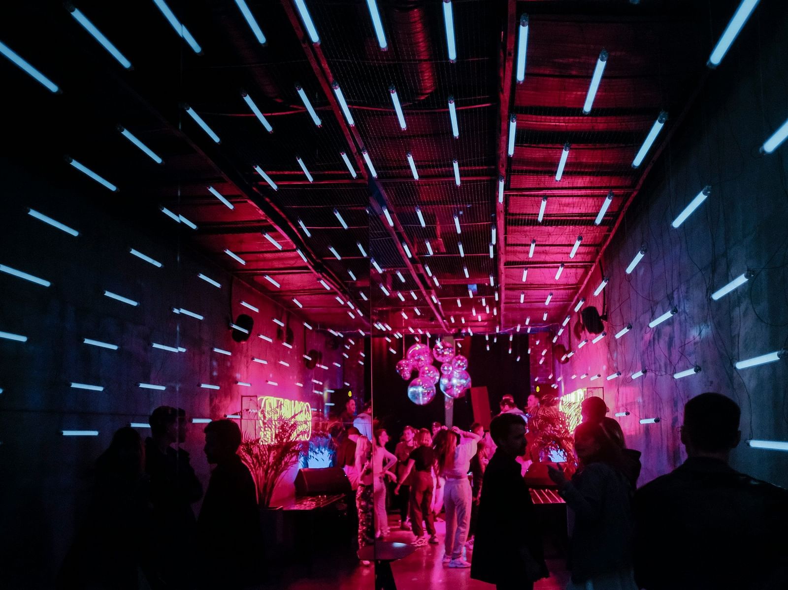 A group of people at the entrance of a dance club with led lights around