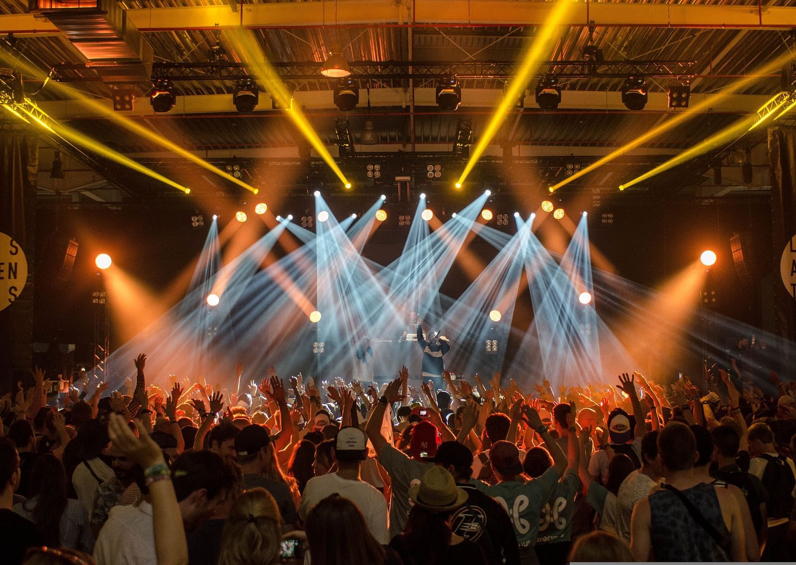 An overview of a concert with a crowd of people dancing to the music being played on the stage.