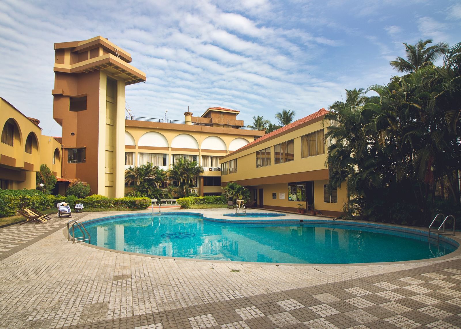 A view of the outdoor swimming pool at Paradise Isle Beach Resort, Udupi with the resort in the backdrop during the day