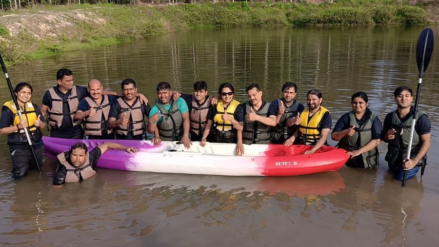 Group of corporate team members in a large kayak, smiling and posing with paddles on a river - Evergreen County