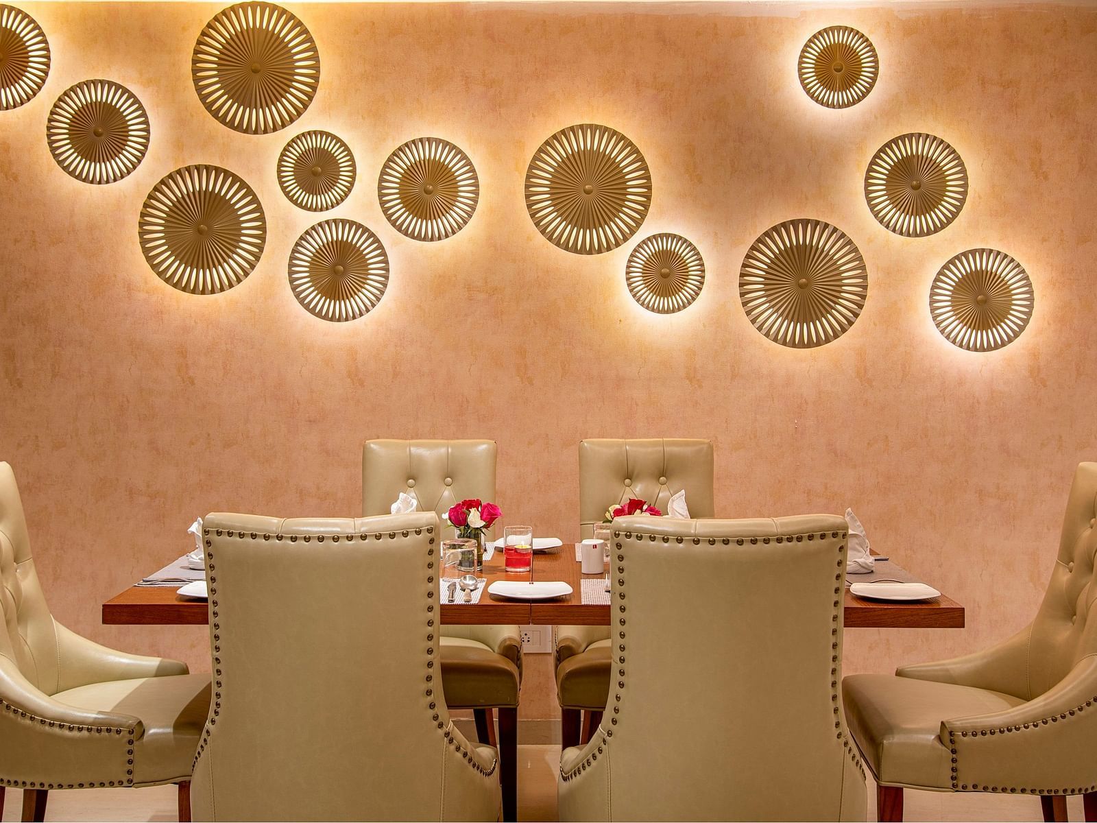 A private dining room with a decorative wall and a set table for a intimate gathering - SK Lords Inn Ahmedabad