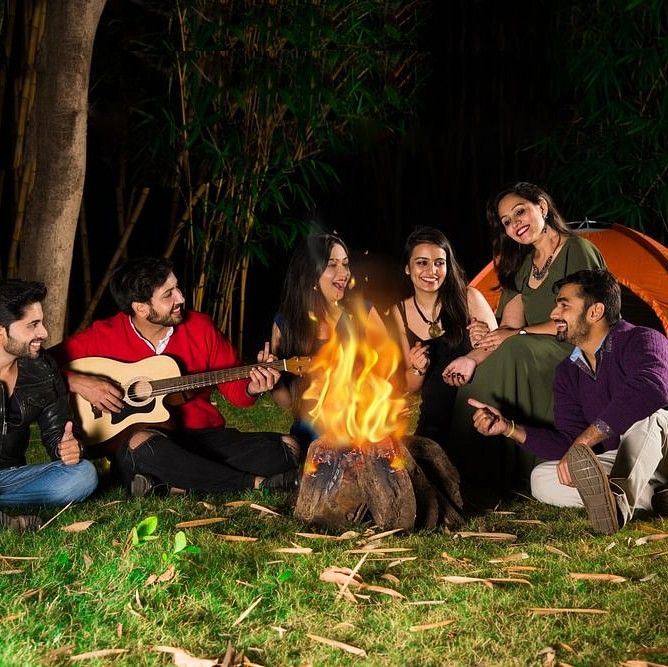 Group of Friends sitting in a circle around a fire camp