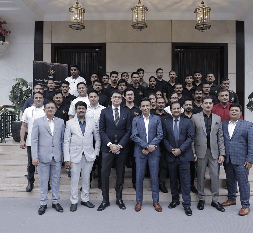 A group of people dressed in business formals gathered together in front of a hotel building.
