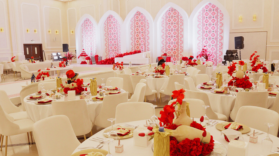 A narrow, vertical view of a decorated banquet hall at La Maison, Doha, showing tables set for dining.