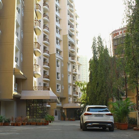 A long shot of the facade of the apartment where a car is heading towards the entrance