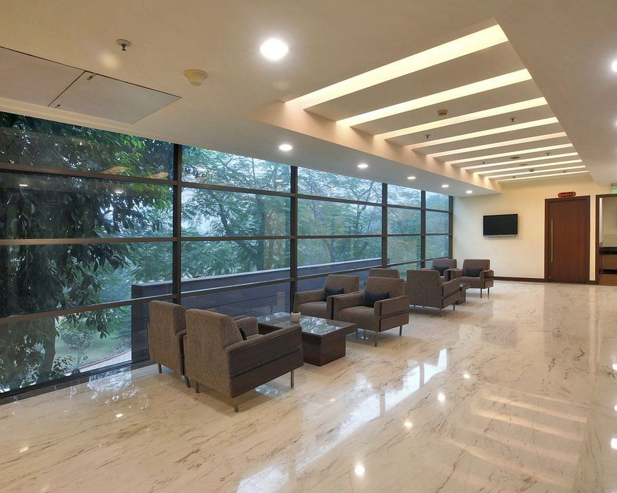 Modern lounge area with comfortable armchairs, large windows overlooking greenery, and a polished floor - Heritage Village Resorts & Spa.