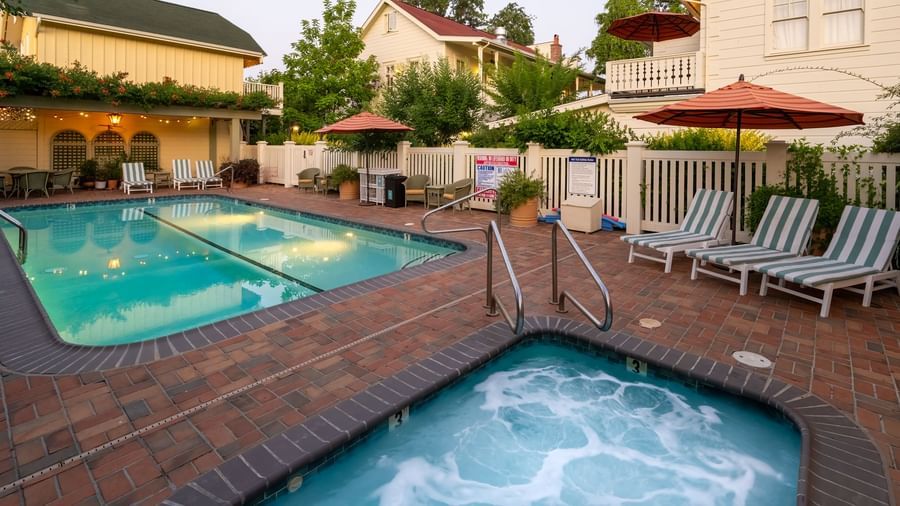 Pair of small outdoor pools at Tallman Hotel with sunbeds and umbrellas.