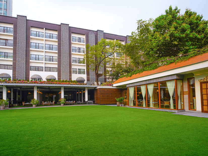 Hotel facade with a manicured lawn and building exterior at Kenilworth Hotel, Kolkata.