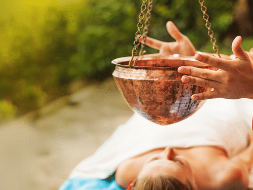 A person lying on their back while a couple of hands holding a hanging pot