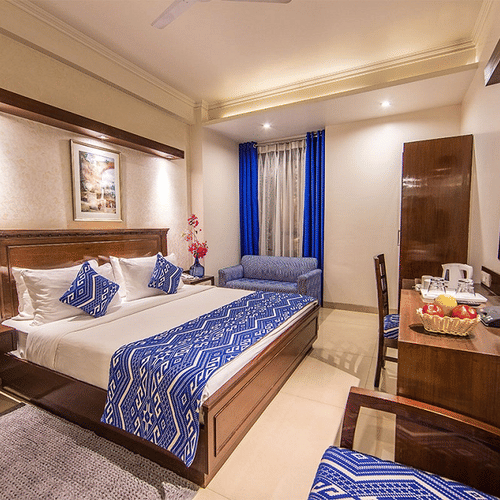 Hotel room at Rockland Hotel, CR Park, with vibrant blue accents, king-size bed, work desk, and modern wooden furnishings.
