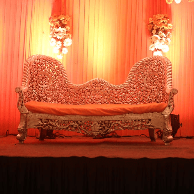 A banquet hall at The Bristol Hotel Gurgaon, with bouquet placed on a table, chairs, and tables .