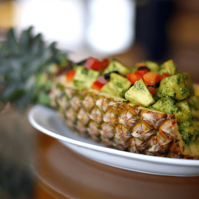 A pineapple cut into half containing a dish with fruits | The Bristol Hotel