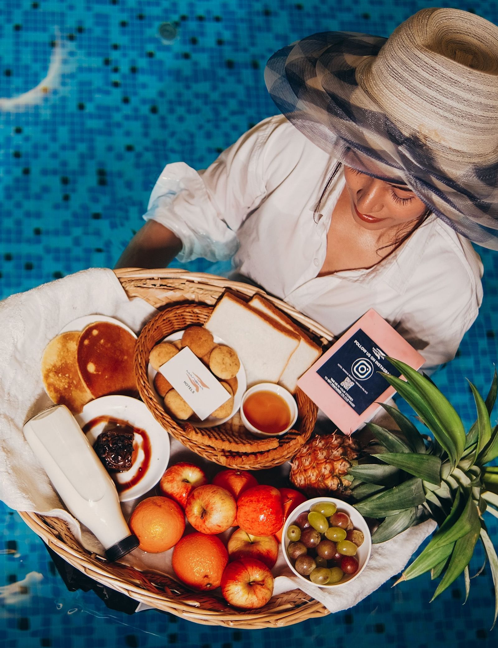 Woman enjoying a floating breakfast tray in a pool at Mansha Regency, Port Blair.