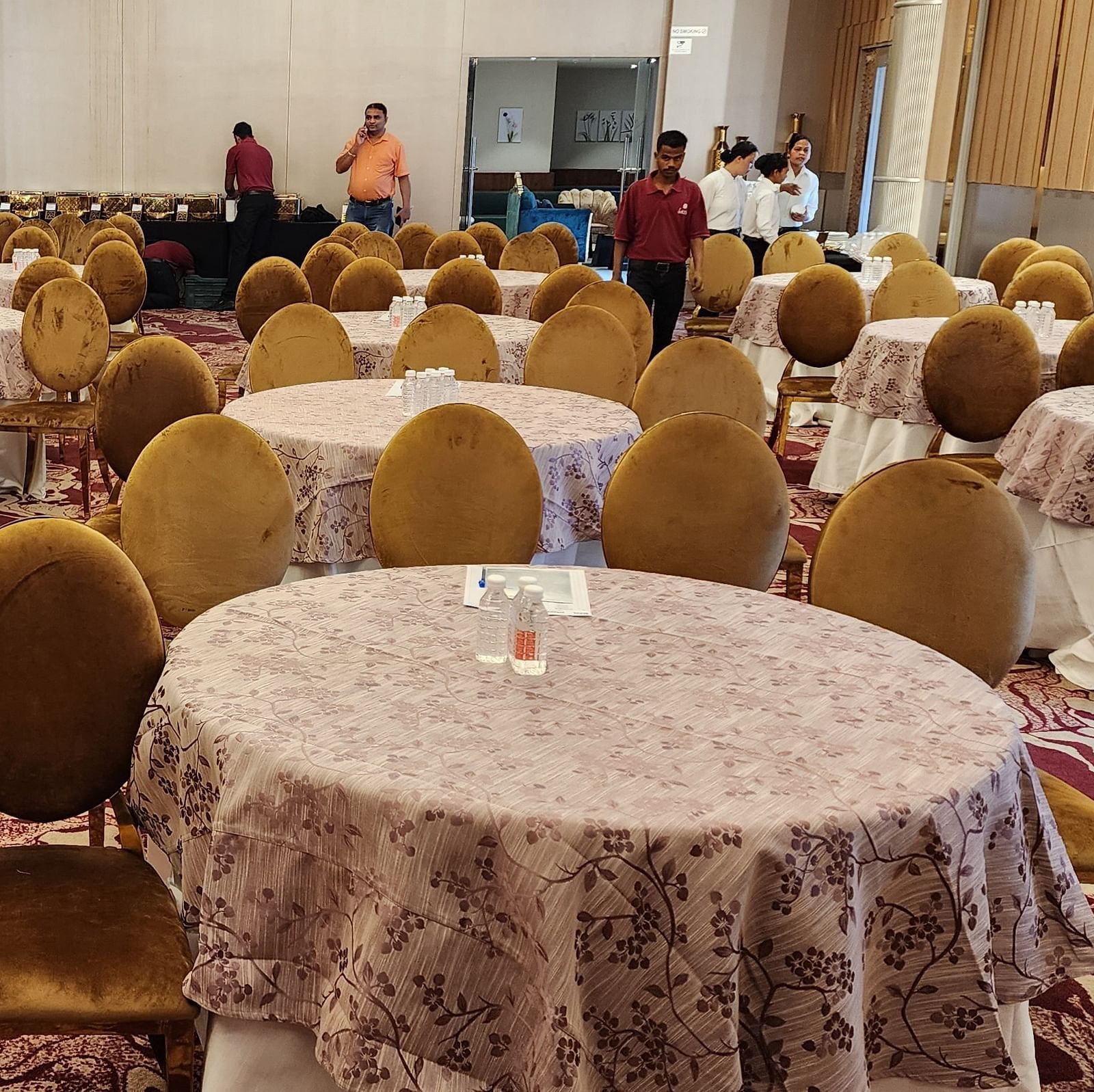 a closeup shot of a banquet hall in Lords Inn Rajkot with cluster seating arrangement and a buffet counter at the back