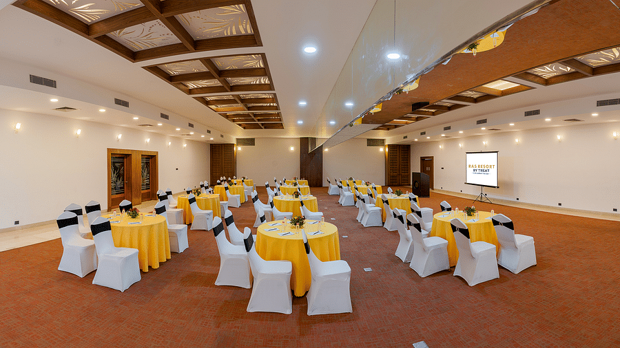 A spacious banquet hall at Ras Resort by Treat, Silvassa, with round tables set up for a meeting or conference.