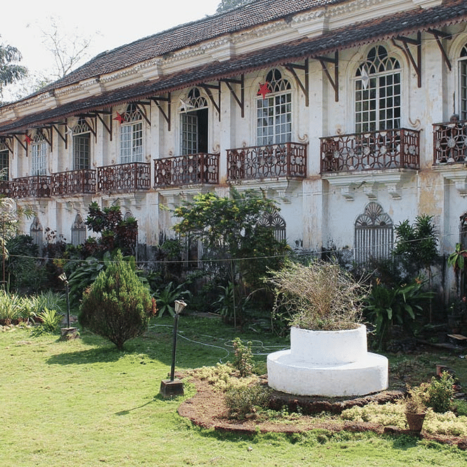 facade of Braganza Pereira House in Goa with a manicured garden in front of it