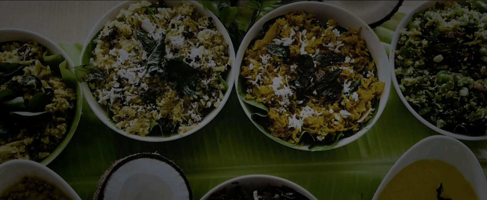 A close-up of four white bowls filled with bright green and yellow Indian chutneys, likely a pickle or condiment.