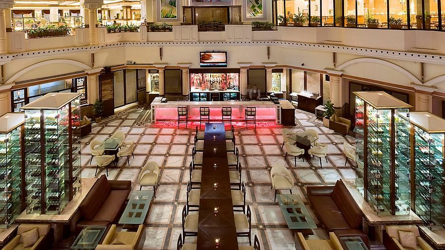 An image of a bar with many multi storey glass cabinet where liquor bottles are kept - The Suryaa New Delhi