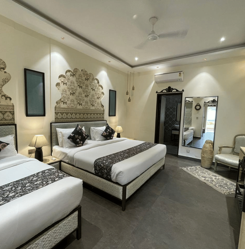 2 single beds with wall decor and lamps beside a mirror and armchair at Beelwa Palace, Jaipur