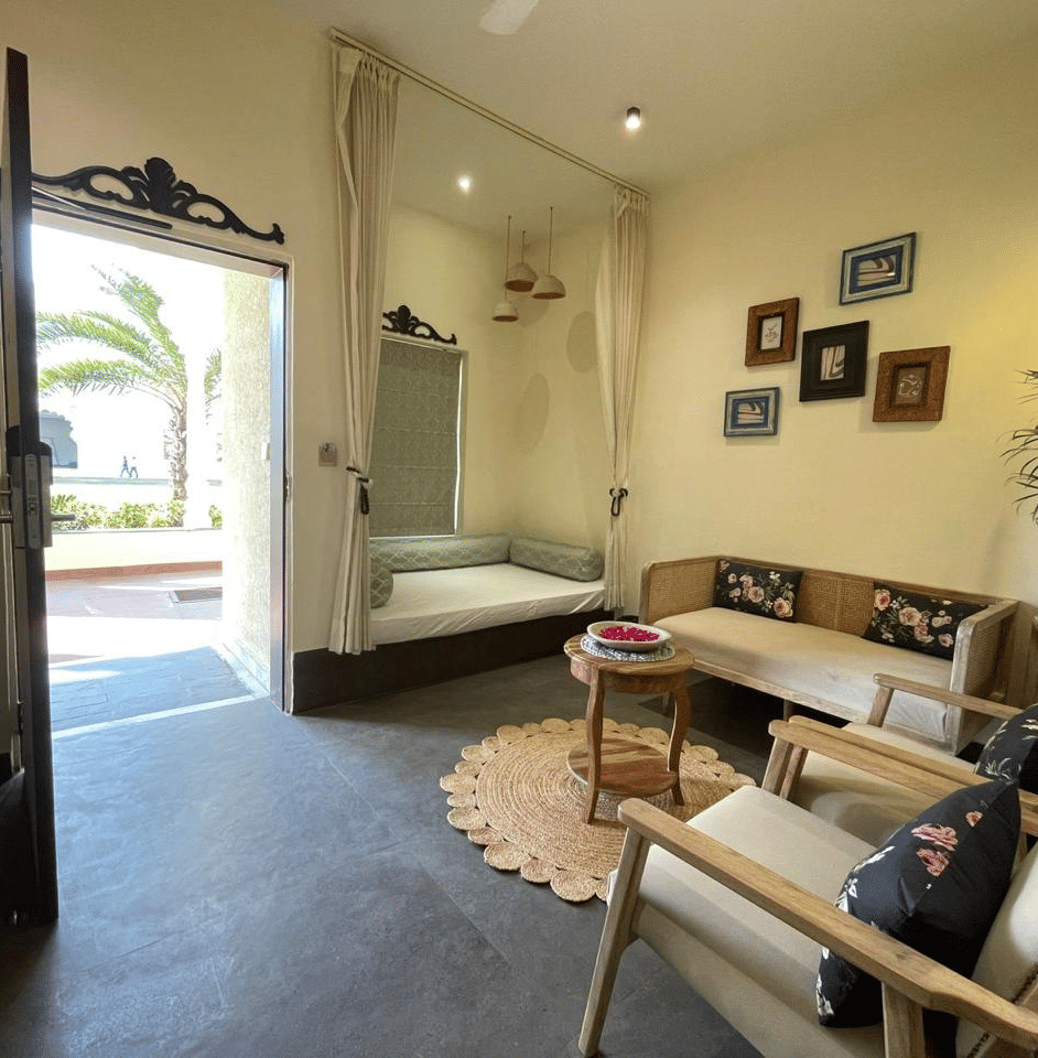 Indoor seating area with sofa, table, open doorway and wall art at Beelwa Palace, Jaipur
