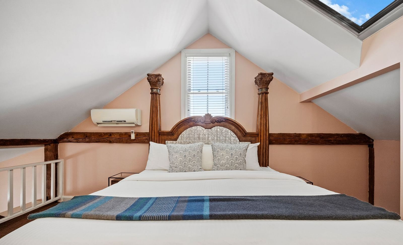 A bedroom with sloped ceiling, skylights, and carved wooden bed at Hartstone Inn.