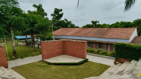 A circular paved gathering area surrounded by grassy areas and a red brick building in the background | Nandan Resort