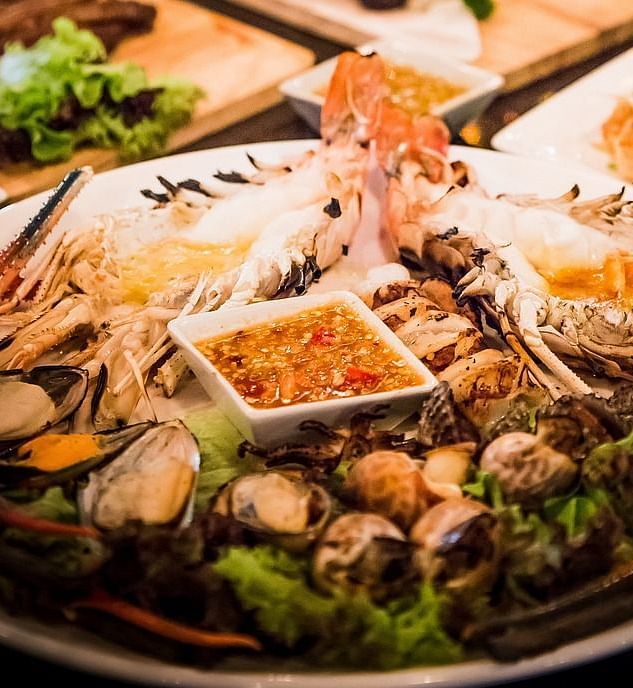 A dining table with seafood served with two glass of white wine