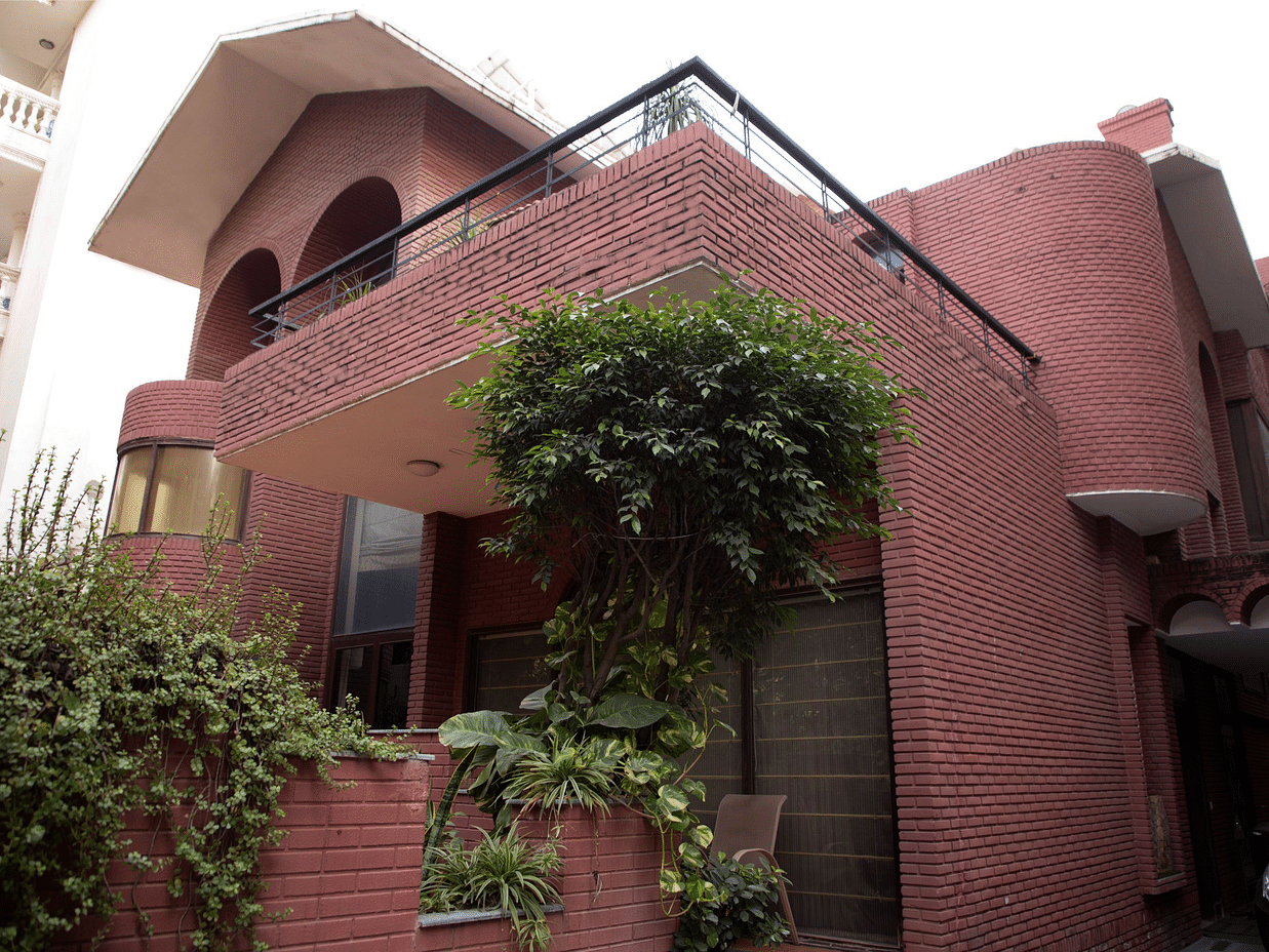 Redbrick Home - image of the facade featuring walls made from red bricks and plants growing in the premises