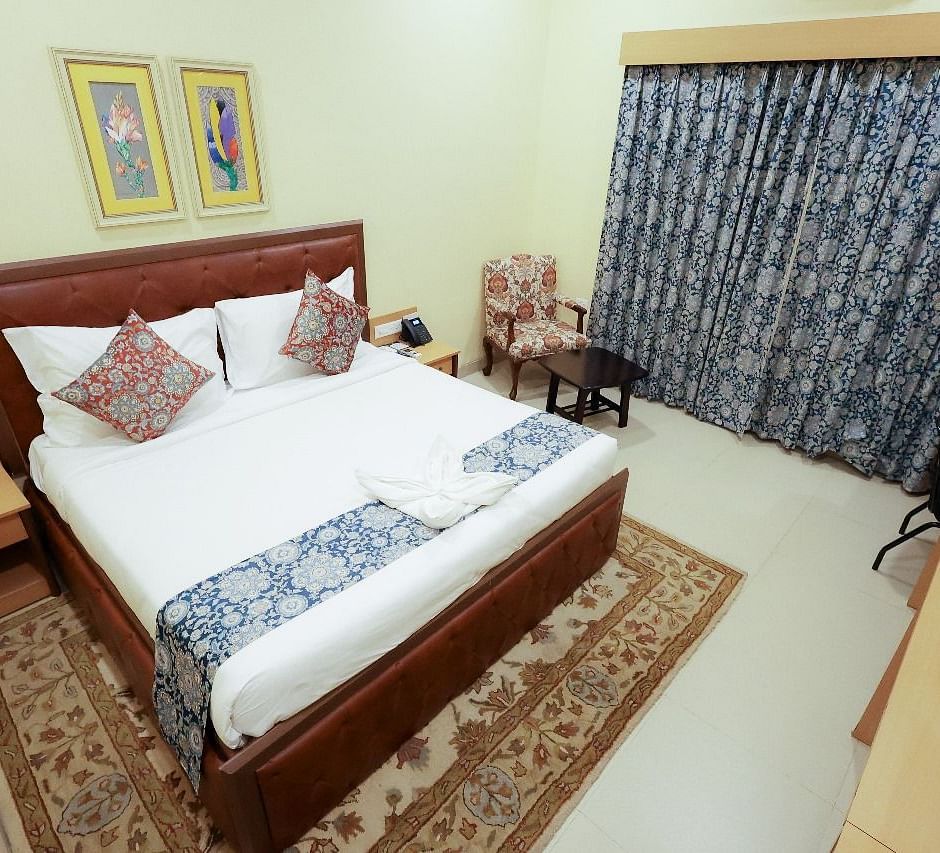 Elegant Deluxe Room at Mayfair World Cup Village, Rourkela, featuring a comfortable bed with patterned decor.