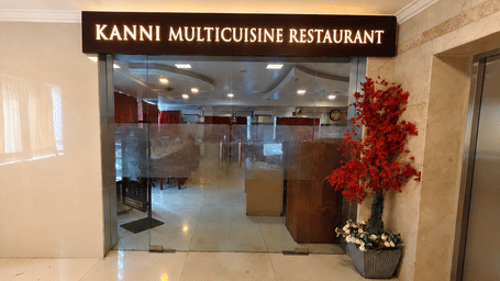 Glass entrance doors displaying a signboard, interior reception desk, and decorative plant at DSF Grand Plaza, Tuticorin.