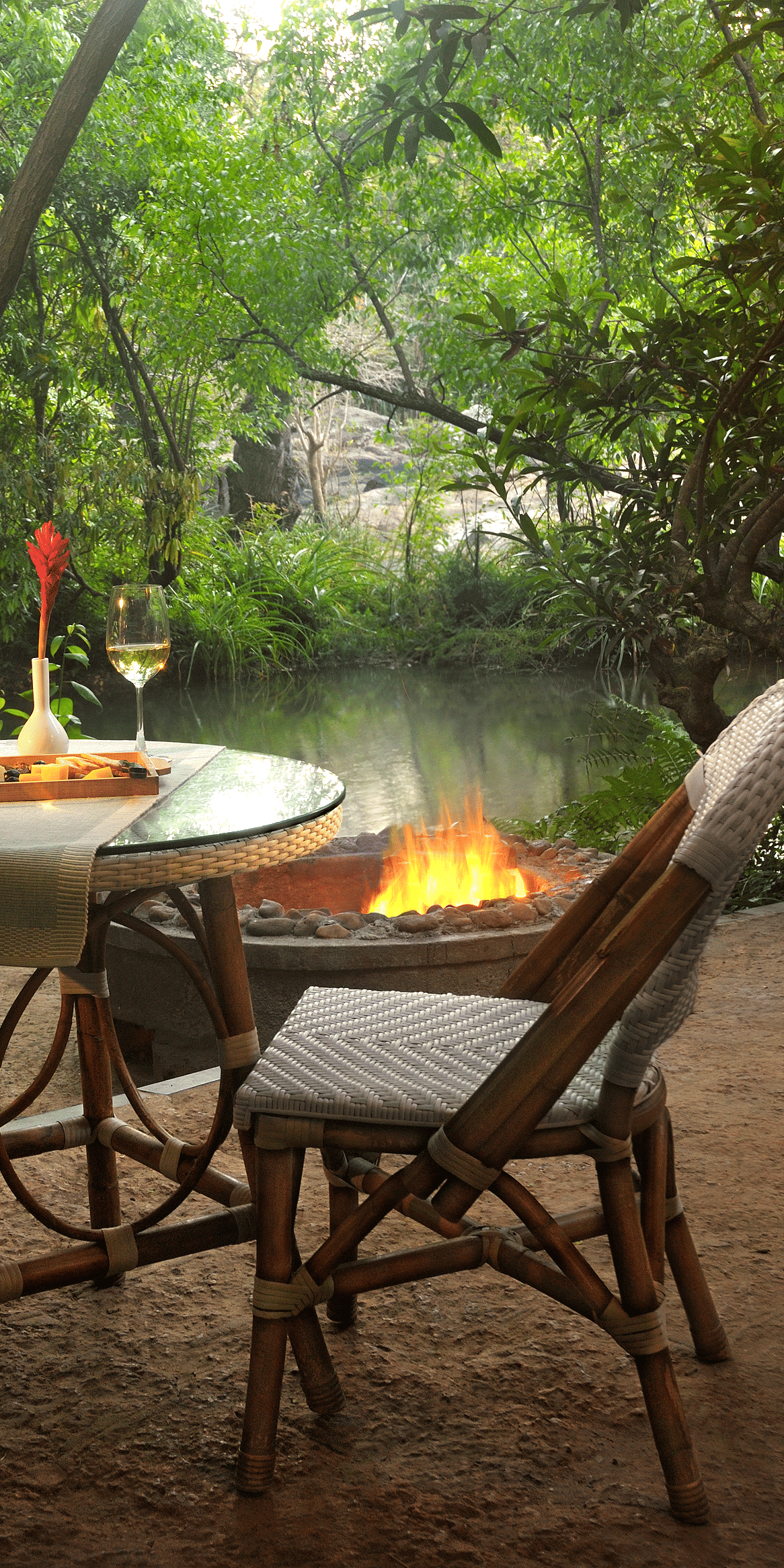 Outdoor dining by a river with a lit candle-Amanvana Spa Resort, Coorg - Luxury Resort