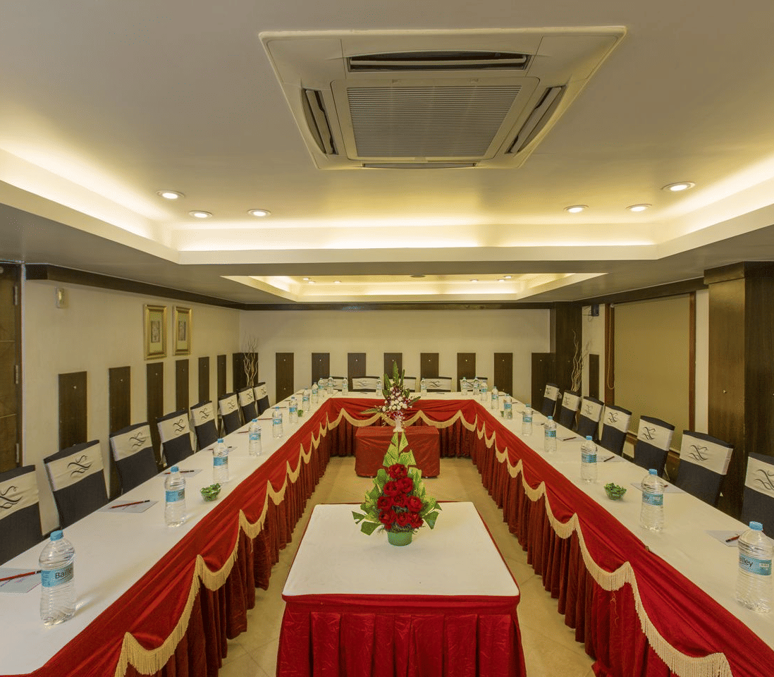 Large conference room with a long table, white chairs, and red runners - The Citrine
