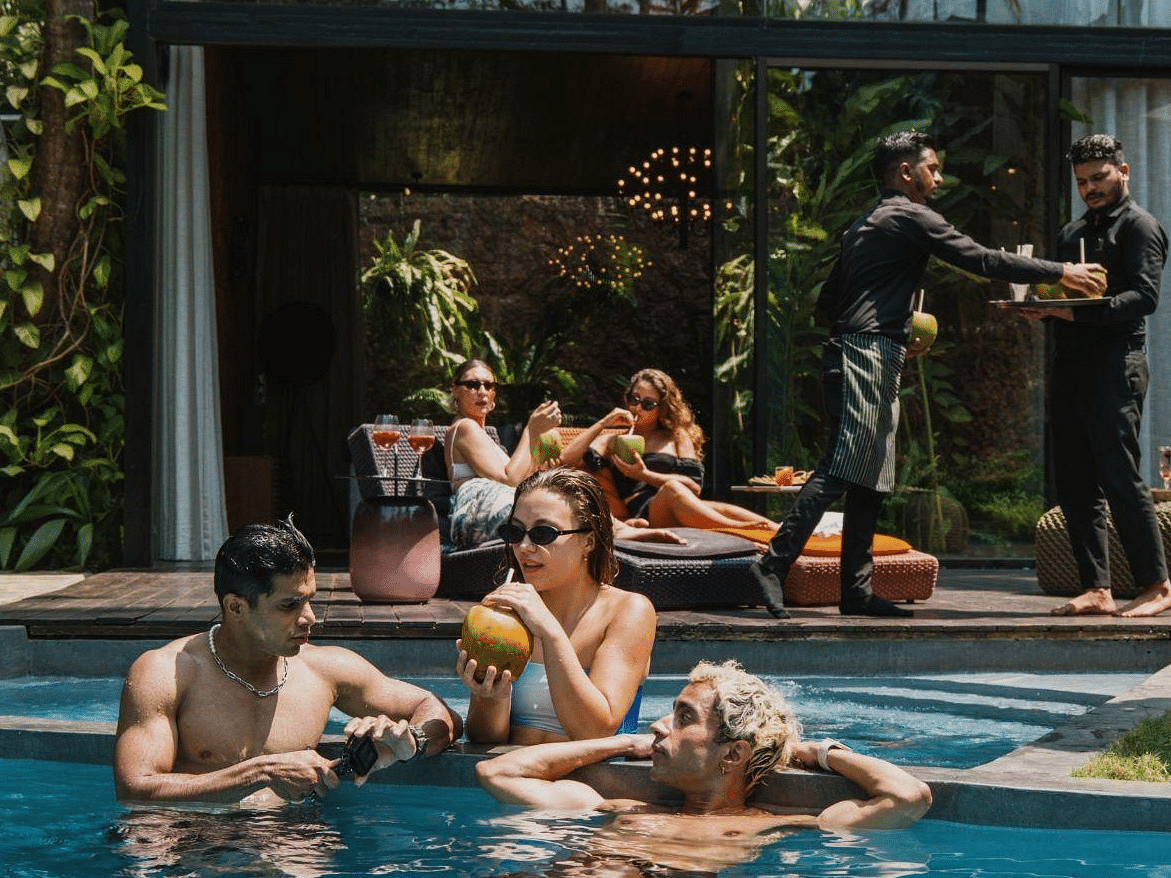 People chilling in the swimming pool under the sun while the rest are relaxing on the deck in the background