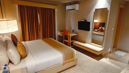 Elegant interior of the Deluxe Double Room at Cholaa Dynasty, Kumbakonam showcasing a cosy double bed, stylish décor, soft lighting, and a thoughtfully designed layout offering a relaxing and premium stay experience in Kumbakonam