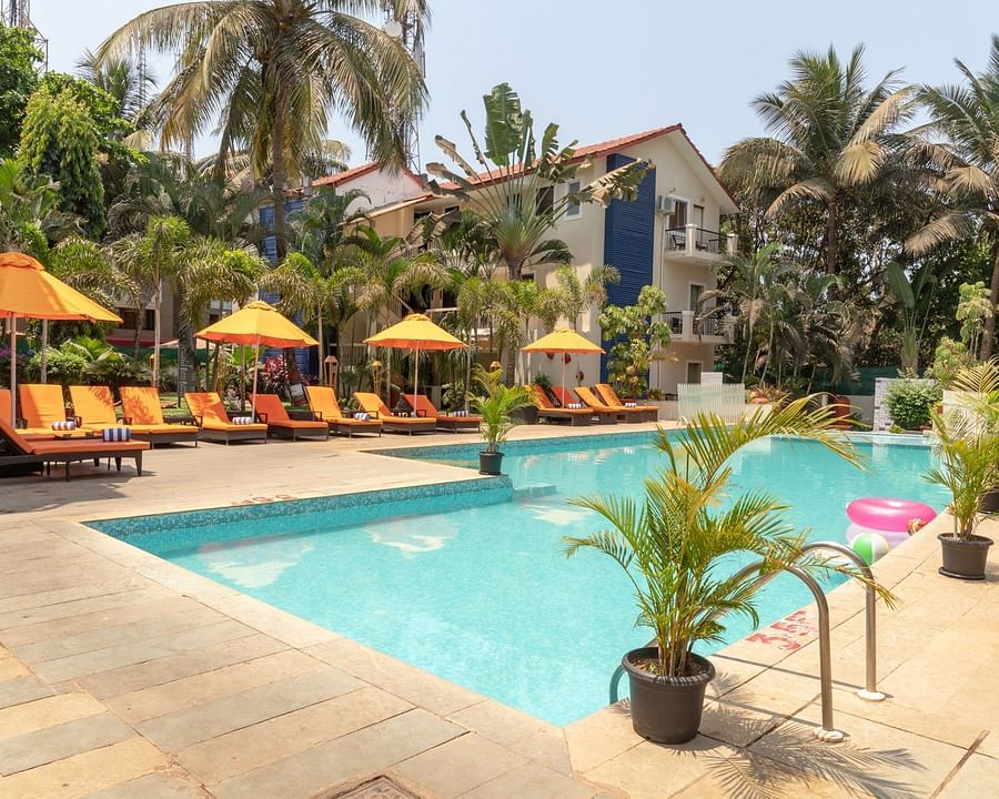 Swimming Pool at Kyriad Prestige Calangute, Goa surrounded by beach chairs