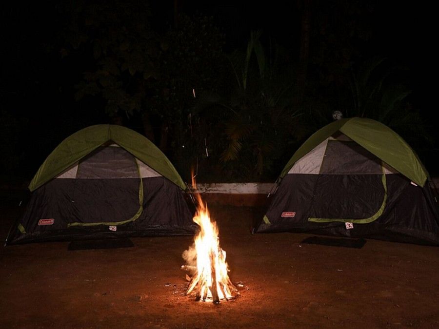 Two tents with campfire in the middle, during the night