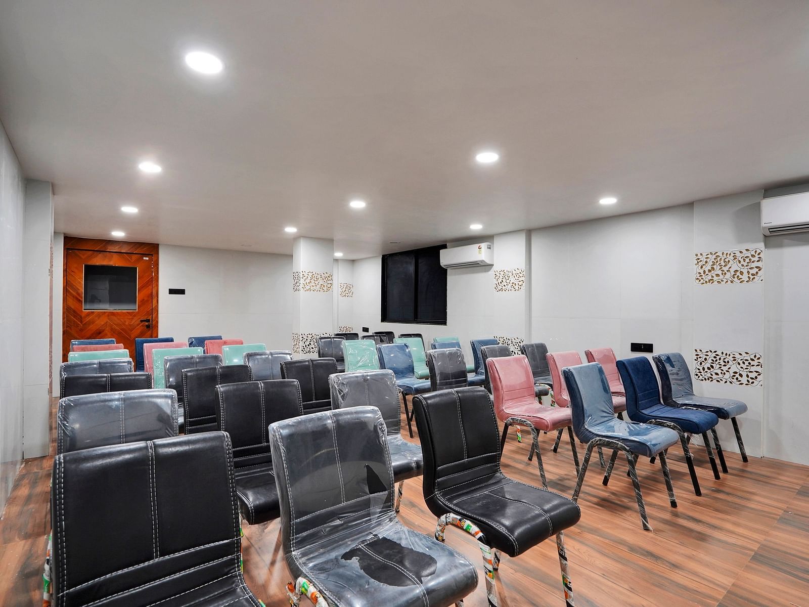 A conference hall with chairs facing the screen at Hotel Regal Heaven, Pune.