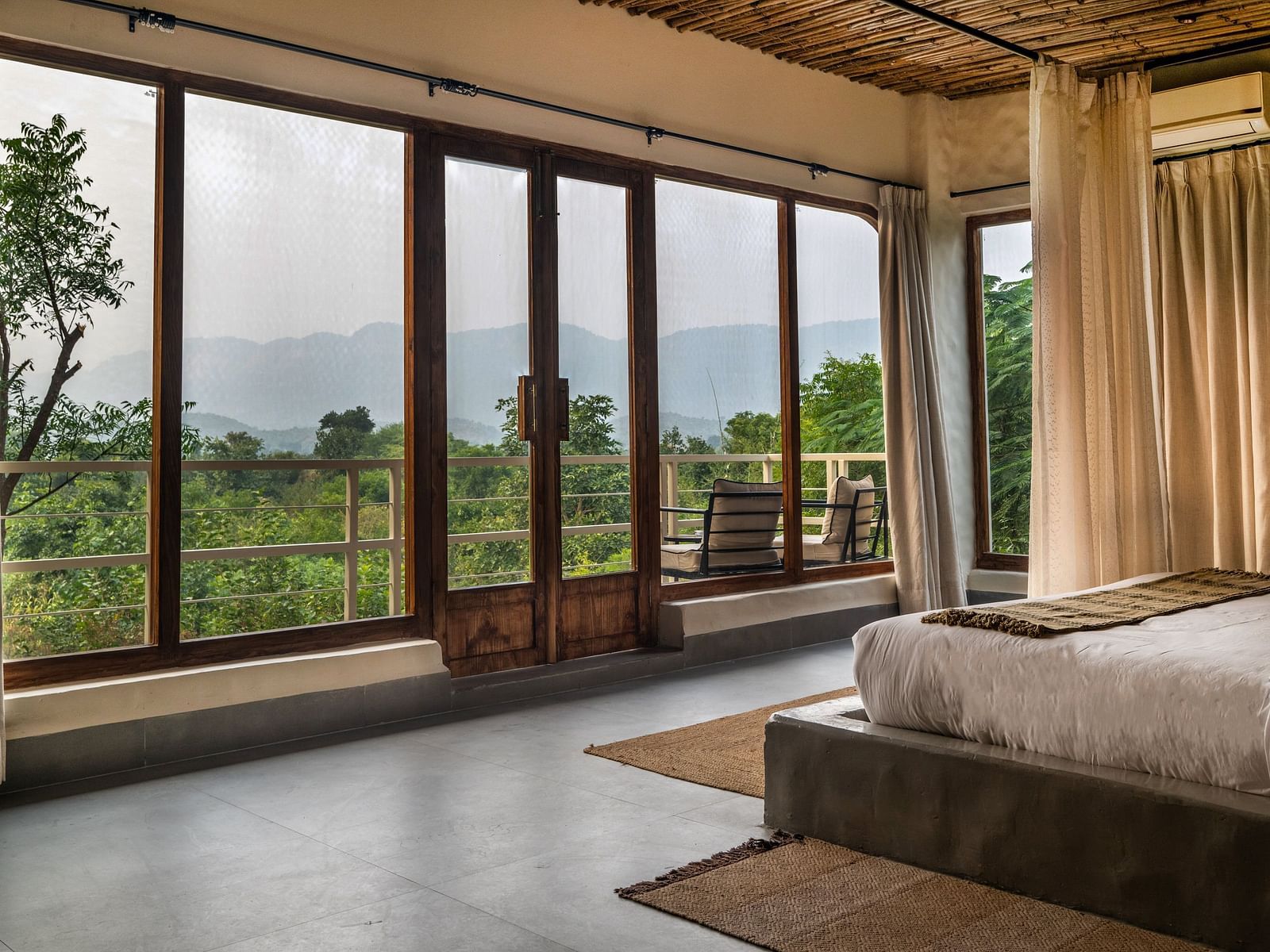 An Interior view of a rustic-style room interior with wooden furniture and floor to ceiling windows.