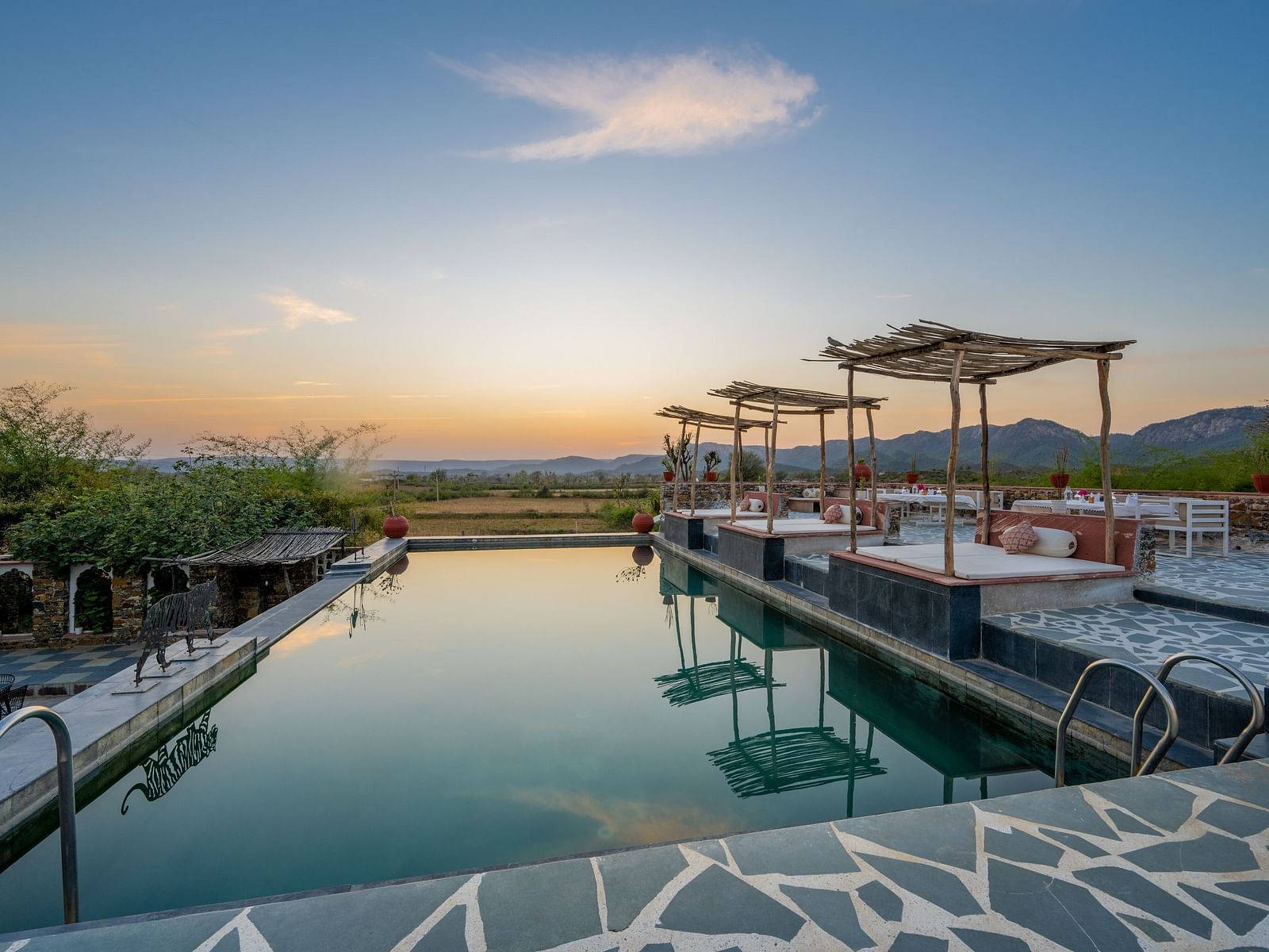 An image of the swimming pool with seating arrangement near it in the open - Utsav Camp Sariska