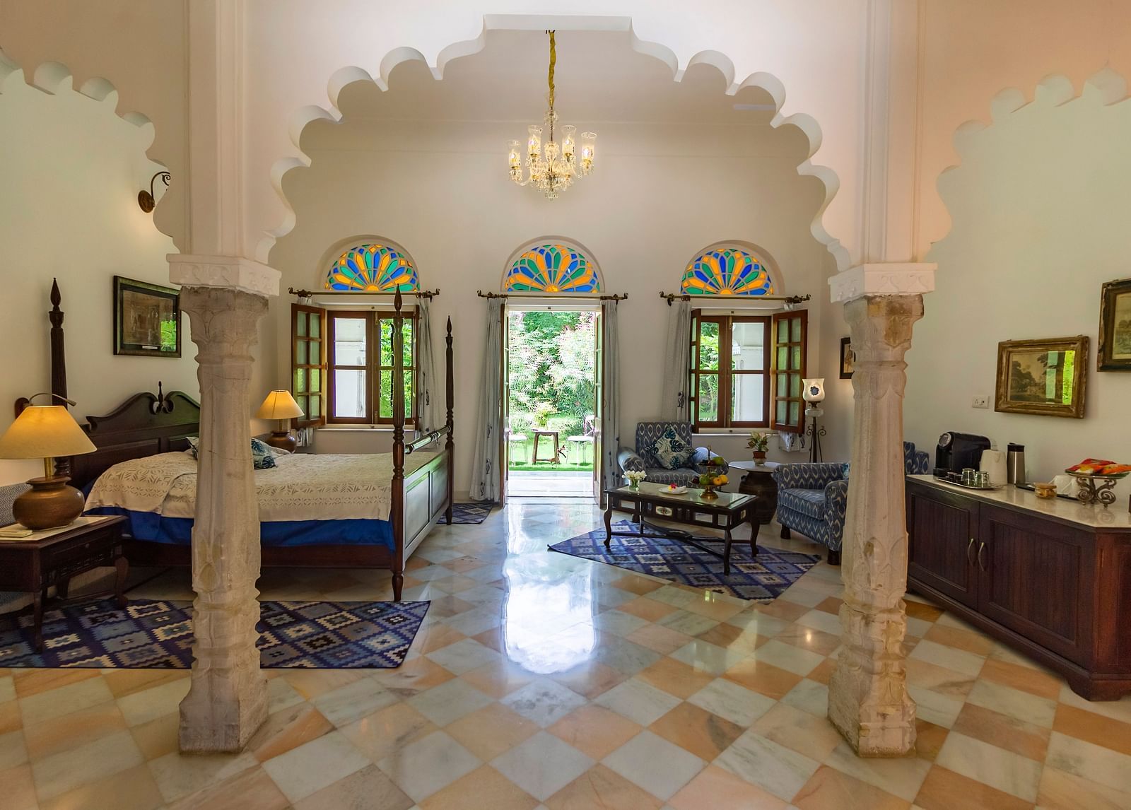 image of the Deluxe suite at Dev Shree, deogarh through the arched pillars featuring a double bed