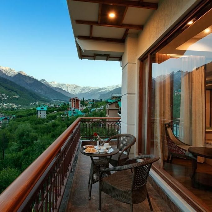 Suite in Manali with an attached balcony overlooking the mountains and greenery