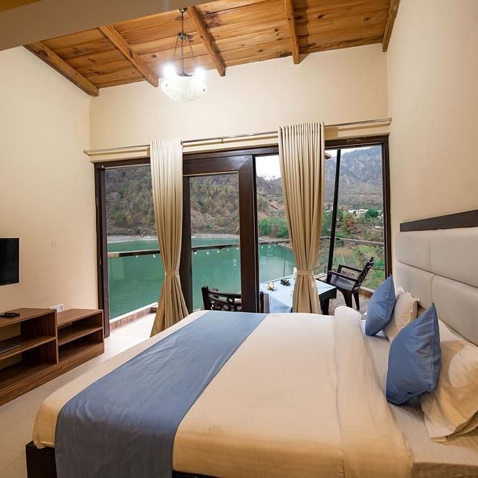 Double bed facing a flat-screen TV and glass doors opening to a balcony 