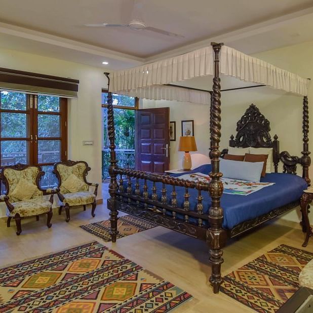 A spacious bedroom with a four-poster bed and a view of the outdoors.