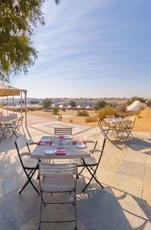 An image of the outdoor dinning area with its seating arrangement and sparse vegetation - MANVAR Resort & Desert Camp