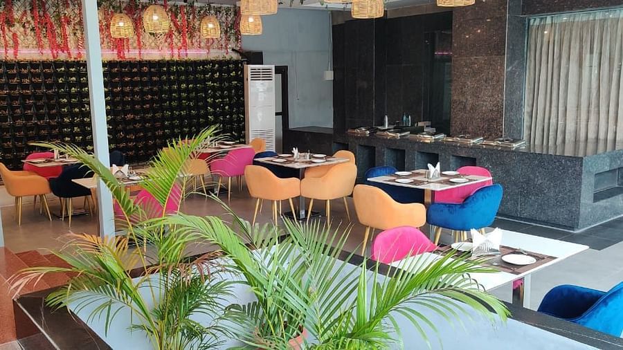 A restaurant interior with colourful chairs, set tables, and decorative plants, showcasing a vibrant dining space - VITS Gurugram