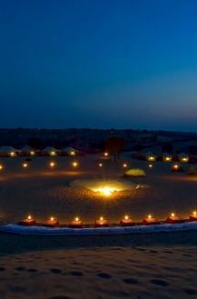 An of the tent area shot at night which is brightly lit with lights - MANVAR Resort & Desert Camp