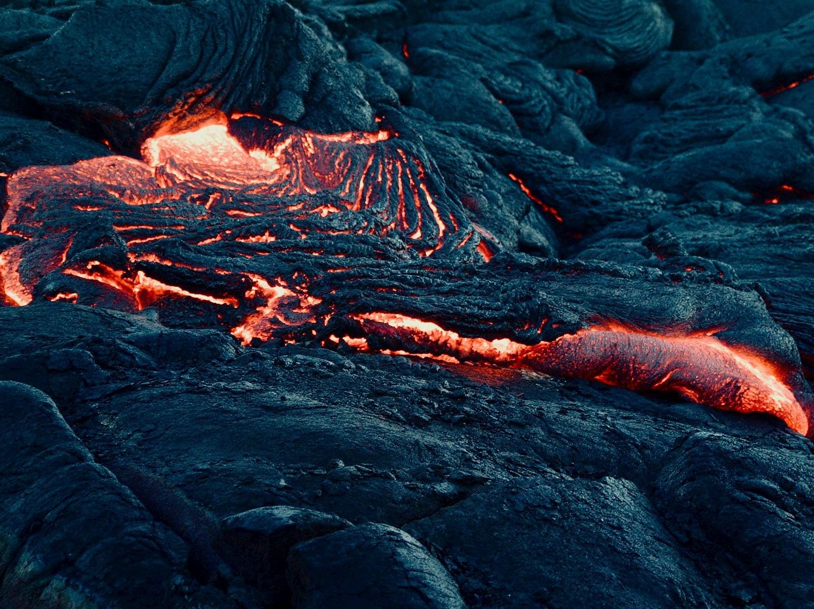 An image of lava flowing through solidified rocks