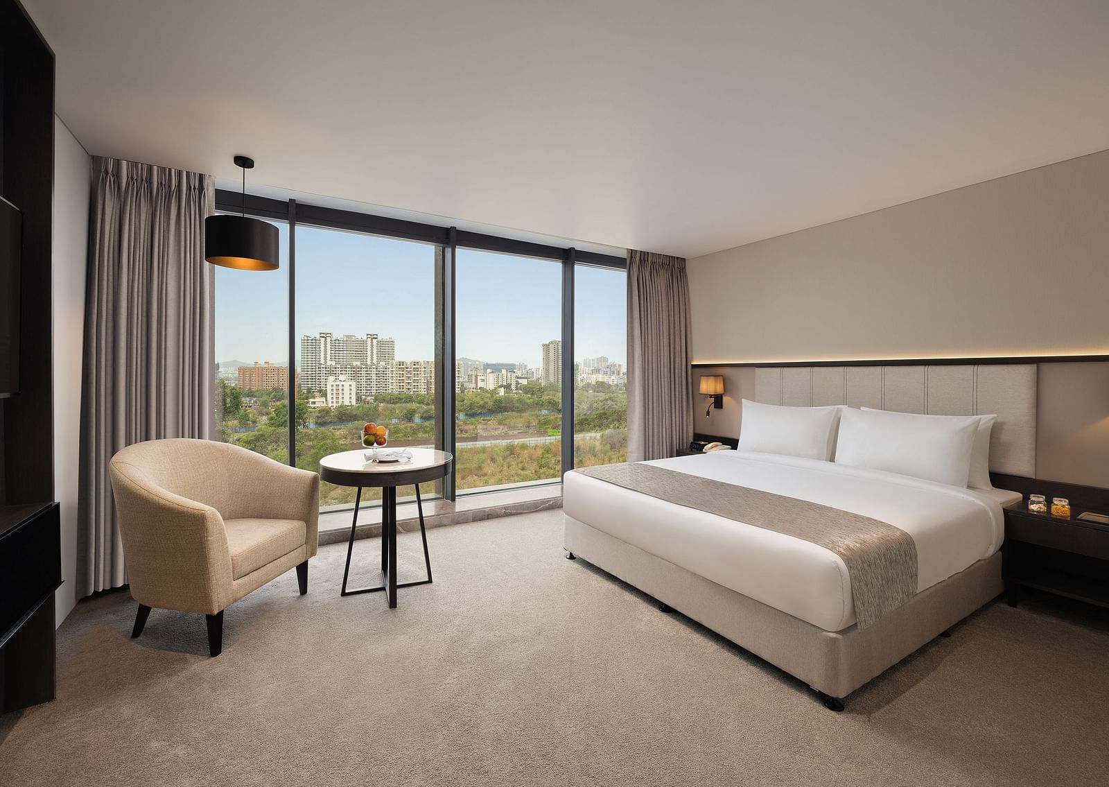  Premier Room with a king size bed and a sofa beside a large window at Essentia Premiere, Pune.
