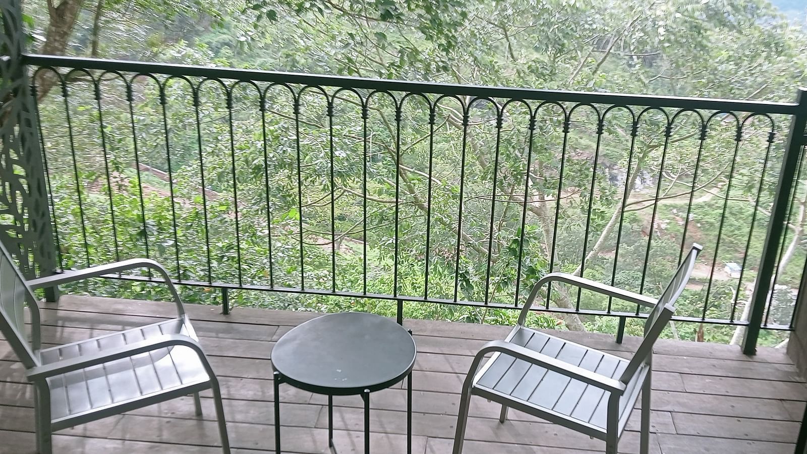 image of the balcony of the artist suite with lush green view from there with a coffee table and two chairs on the porch