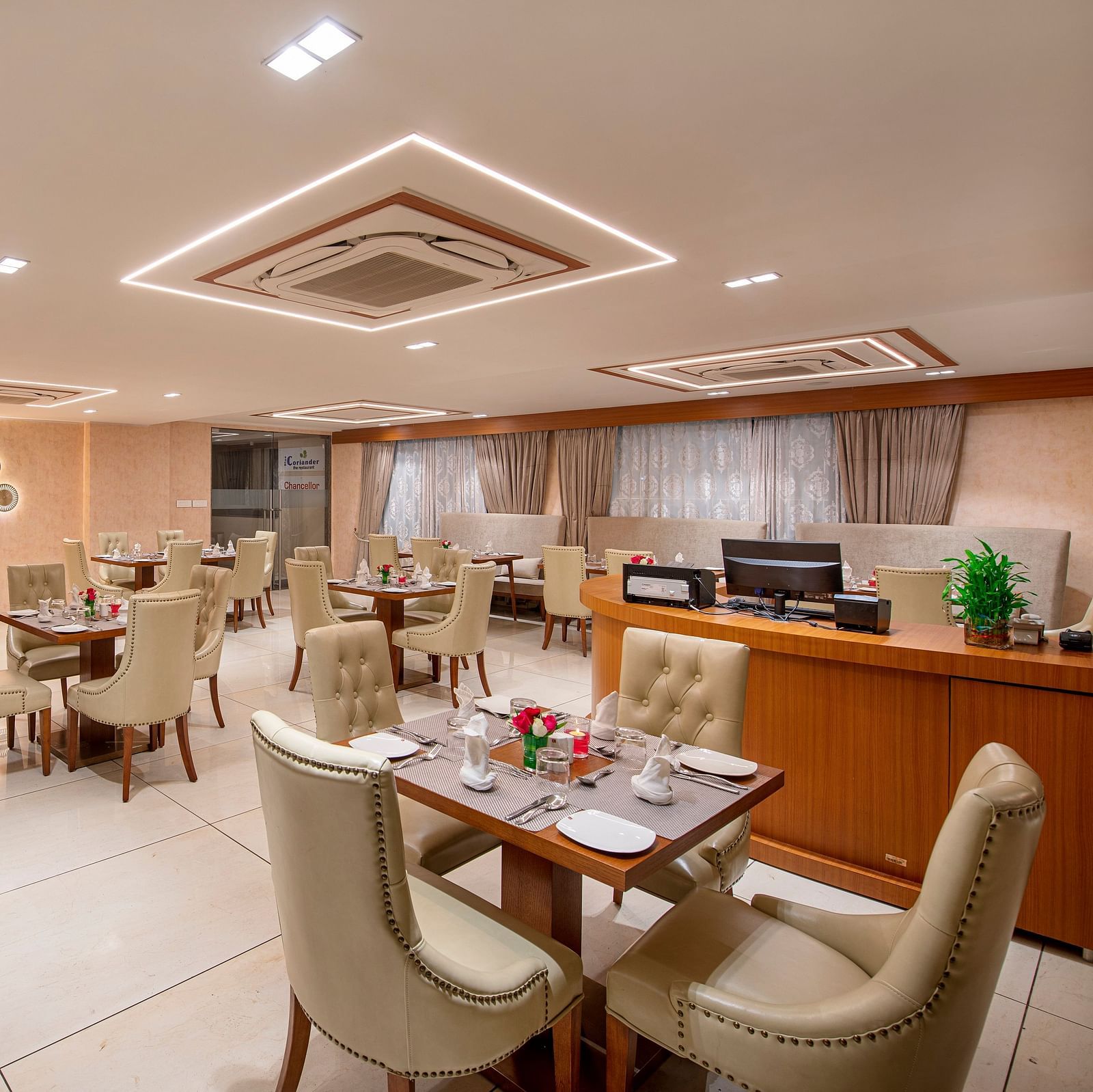 A view of a hotel dining space, showing a mix of table setups and a serving area - SK Lords Inn Ahmedabad